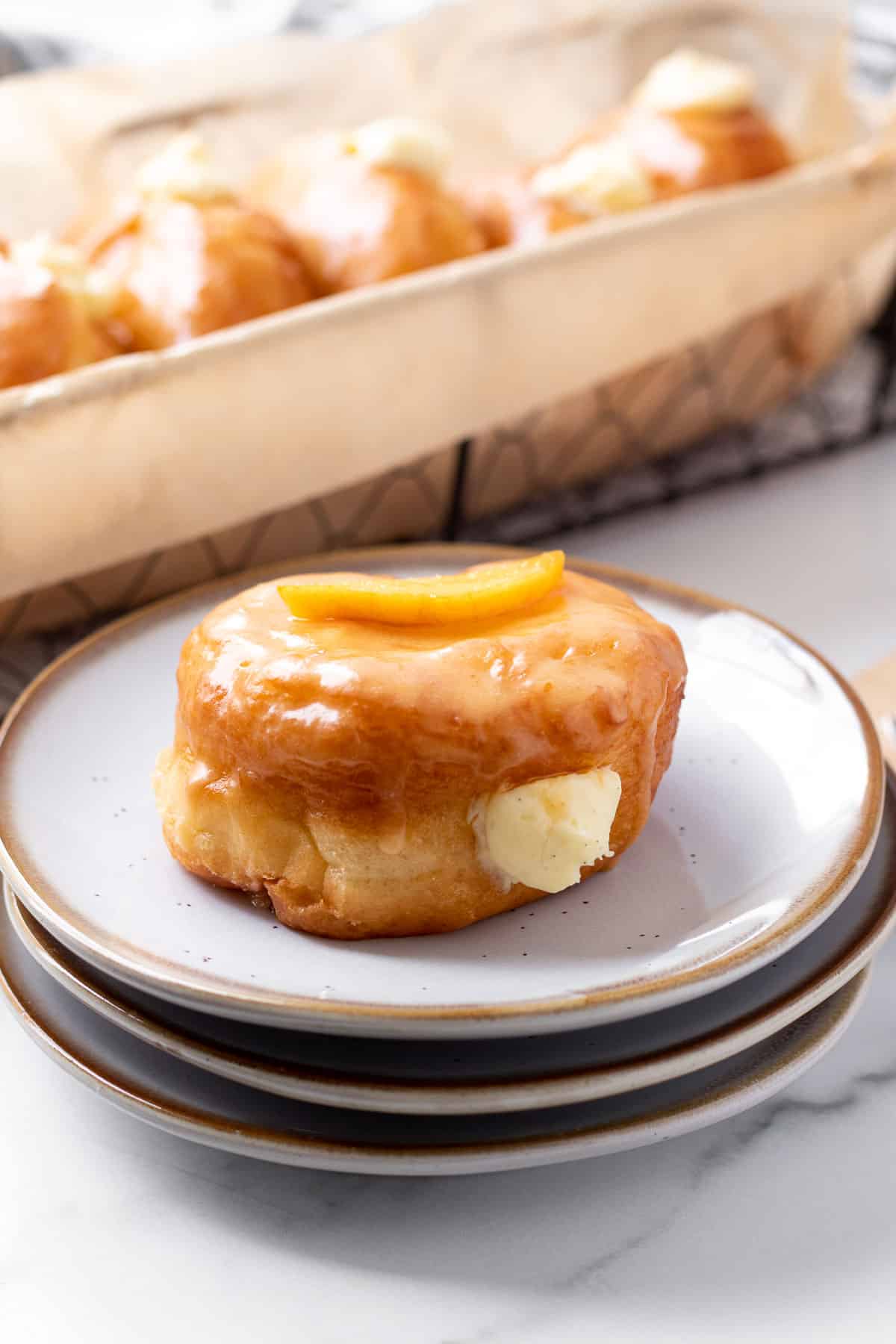 stack of plates with peach donut on top and basket of donuts in background