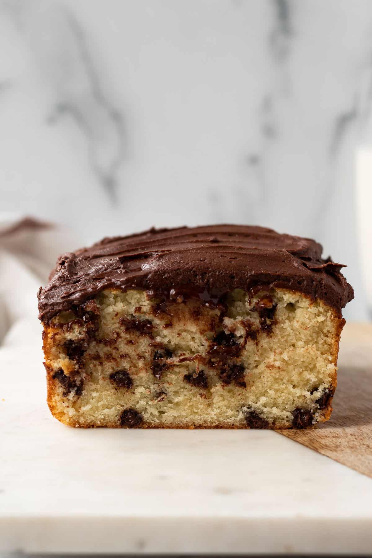 chocolate chip loaf cake frosted with whipped chocolate ganache sitting on a marble slab