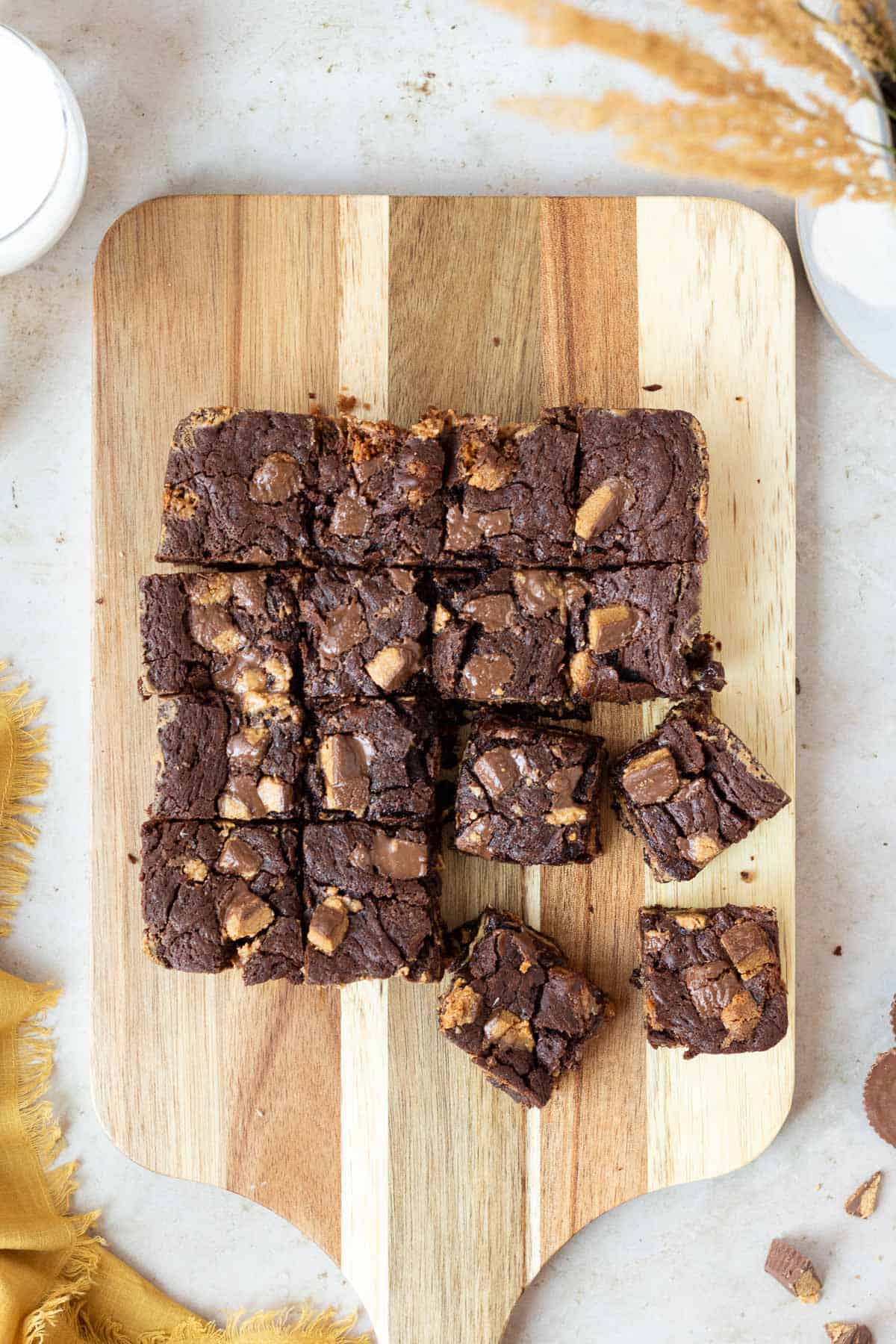 slab of peanut butter cup brownies cut into squares sitting on top of a wooden cutting board