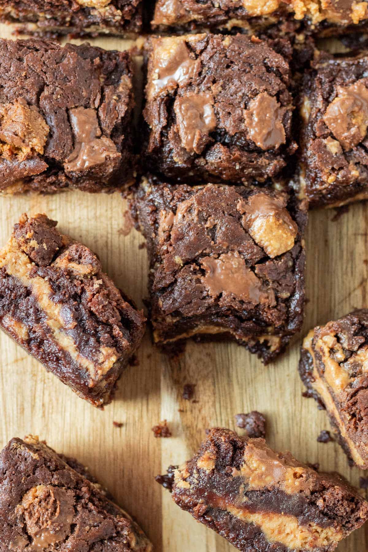 peanut butter cup brownies on a cutting board with some on their side showing a layer of peanut butter filling