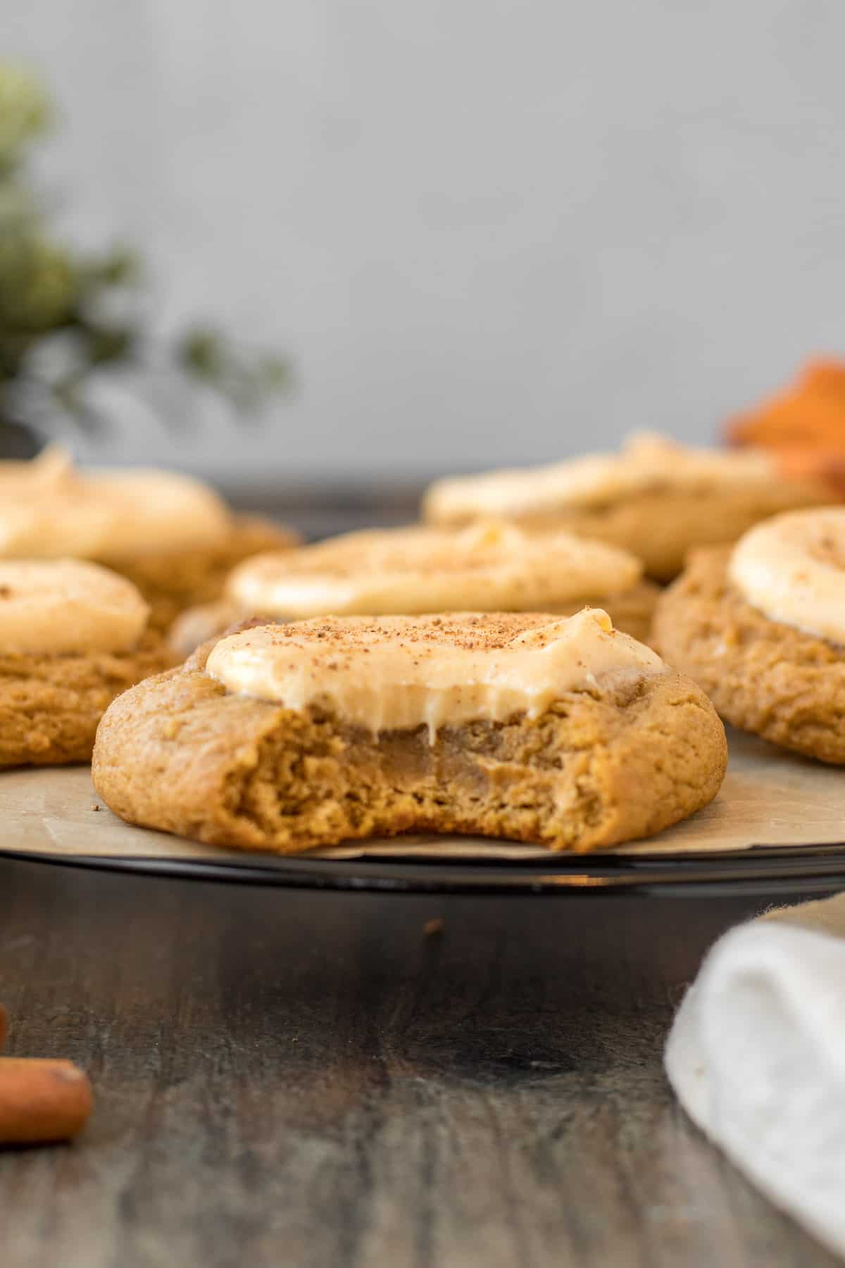 close up view of a pumpkin cookie with cheesecake filling with a bite out of it