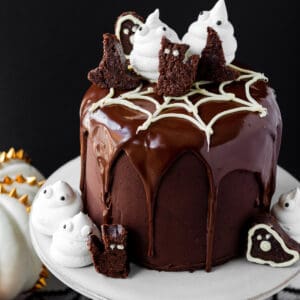 chocolate brownie cake decorated with meringue ghosts, halloween brownies sitting on white cake stand with halloween decor