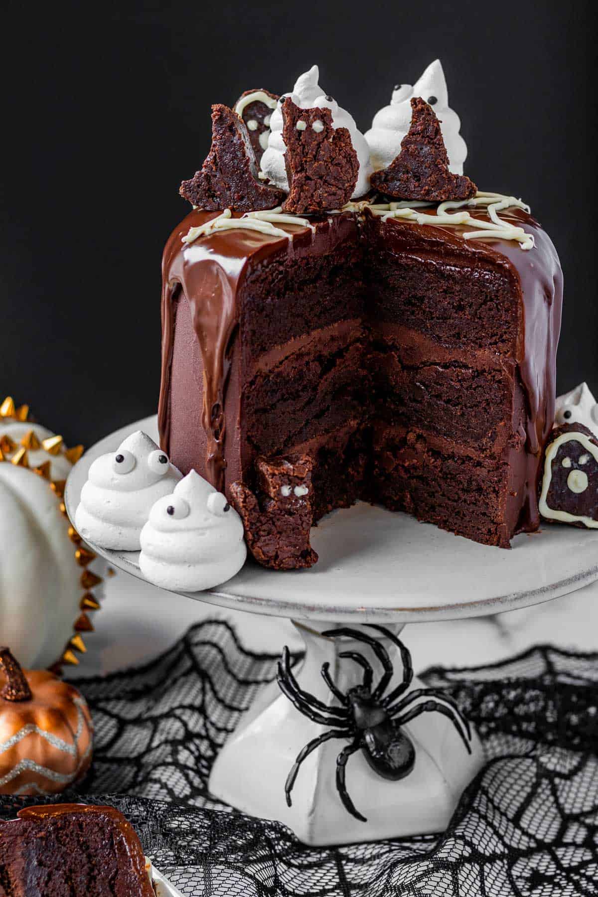 chocolate brownie cake cut open showing layers of cake and frosting with Halloween decor around it