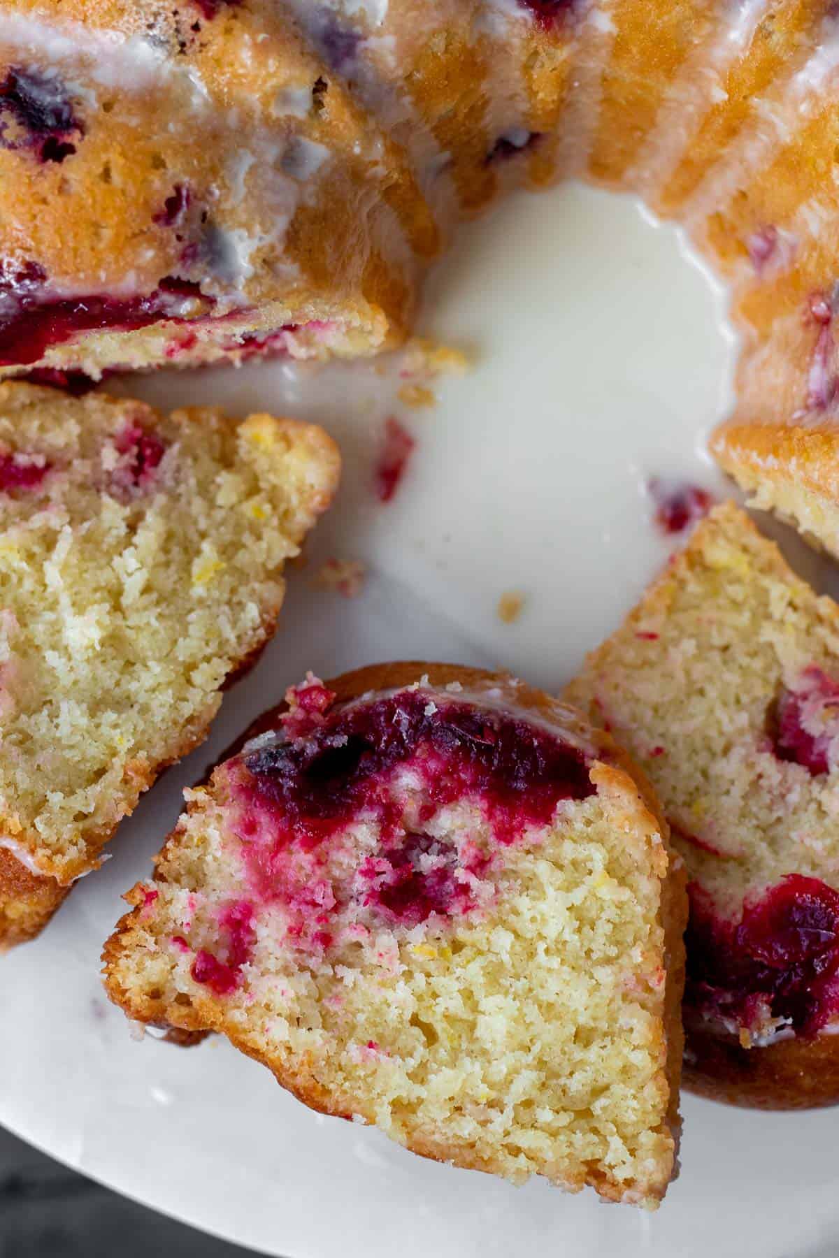 close up of slices of cranberry orange bundt cake on a white marble stand