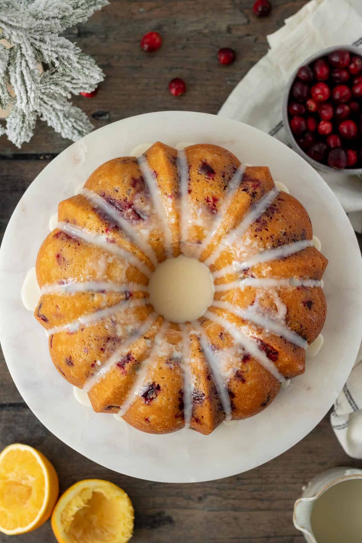 cranberry orange bundt cake on a white marble cake stand on a wood background