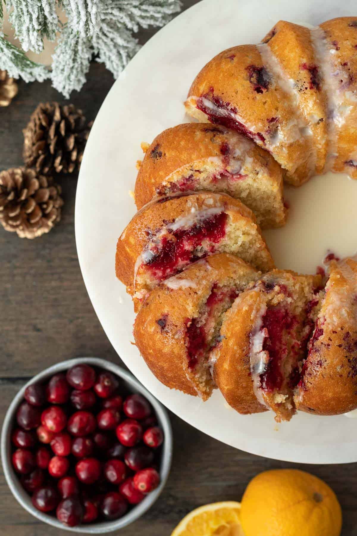 cranberry orange bundt cake slice and spread out on a marble cake stand