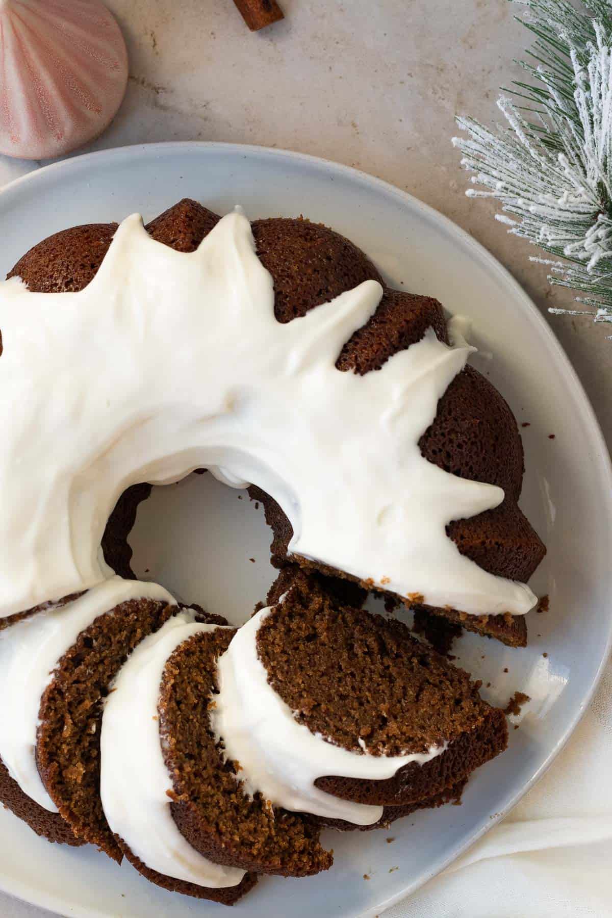 gingerbread bundt cake with a cream cheese glaze on a gray plate sitting on a light brown background