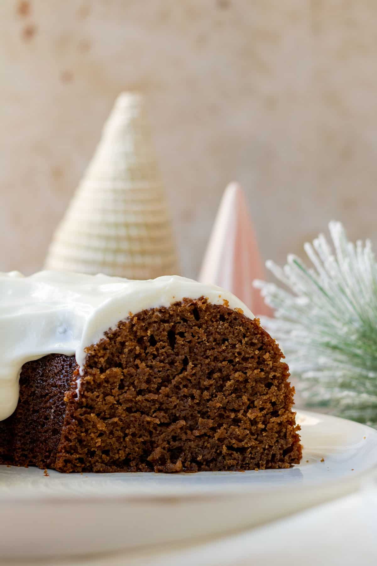 close up of a gingerbread bundt cake sliced open with decorative christmas trees in the background