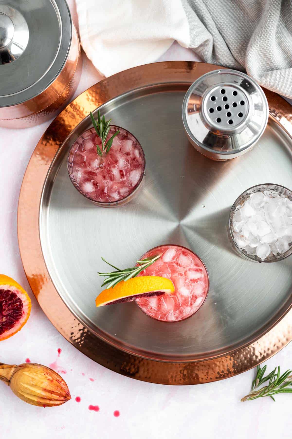 blood orange gin cocktails on a silver and gold tray with a cocktail shaker