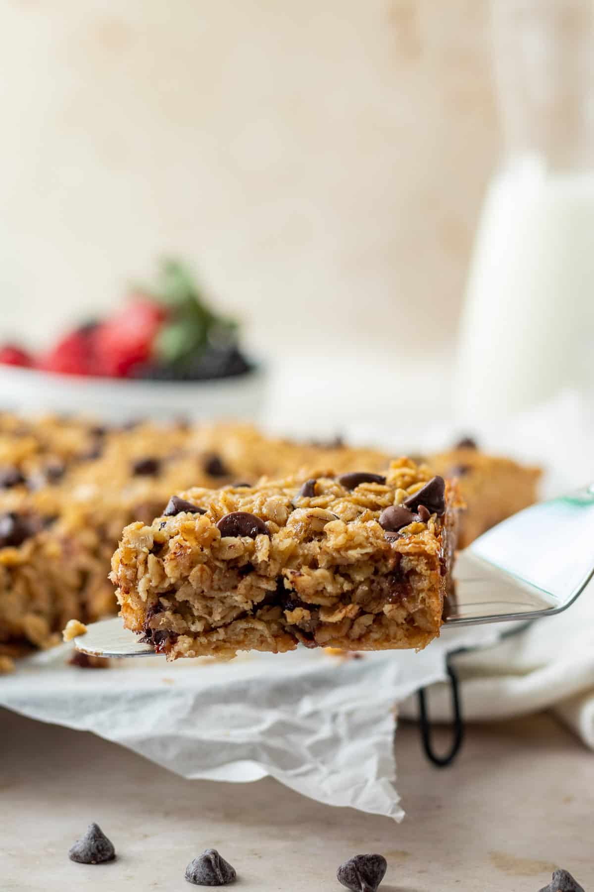 A spatula lifting a slice of chocolate chip baked oatmeal from the cooling rack