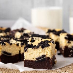oreo cheesecake bars sliced into squares with a glass of milk in the background