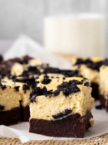 oreo cheesecake bars sliced into squares with a glass of milk in the background