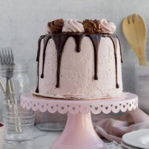 chocolate raspberry mousse cake with dripping chocolate ganache on a pink cake stand