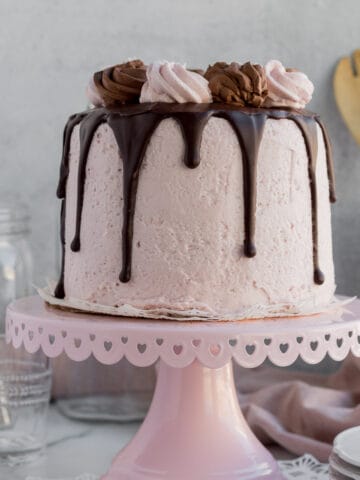 chocolate raspberry mousse cake with dripping chocolate ganache on a pink cake stand