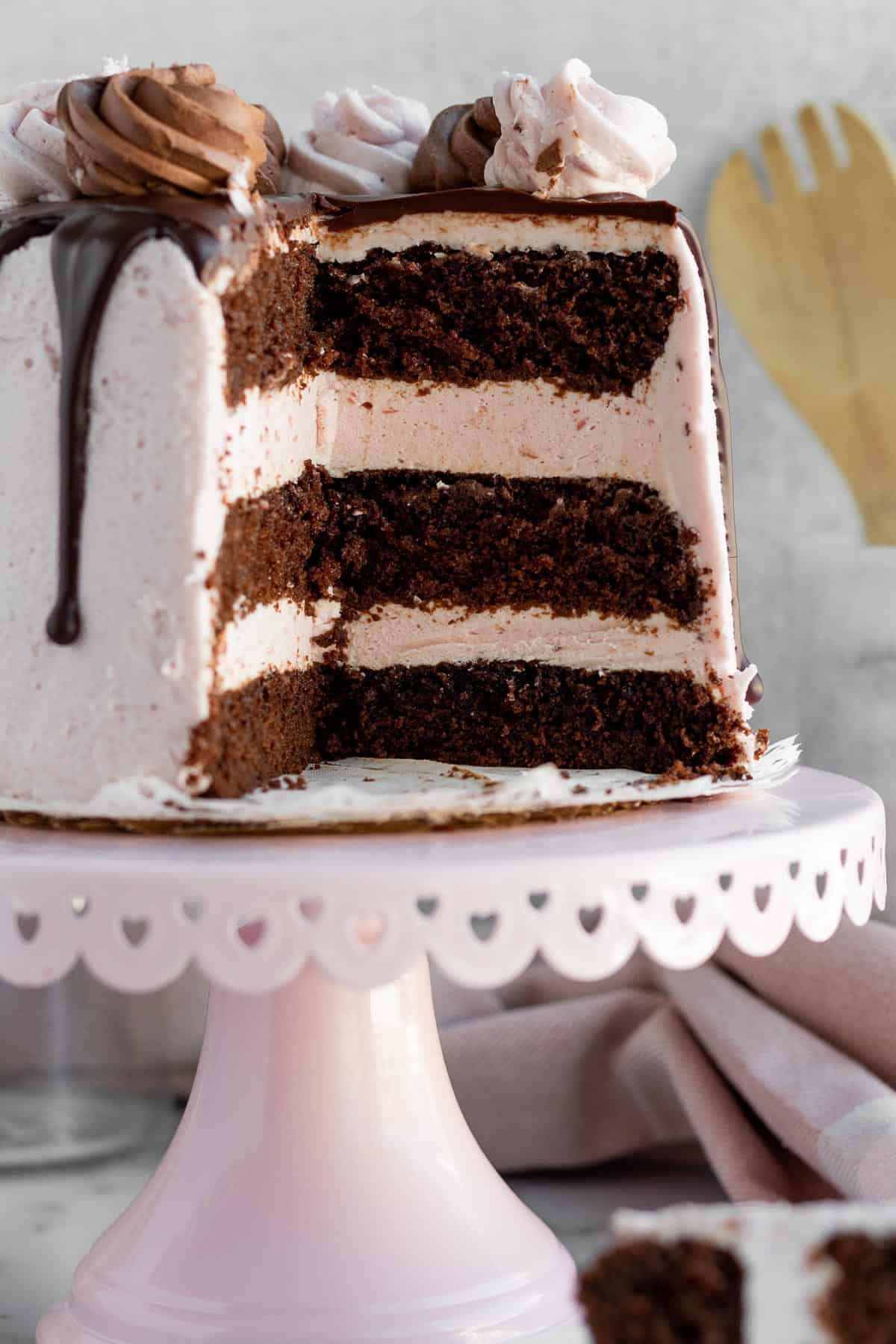 chocolate raspberry mousse cake on a pink cake stand and sliced open to reveal the cake layers