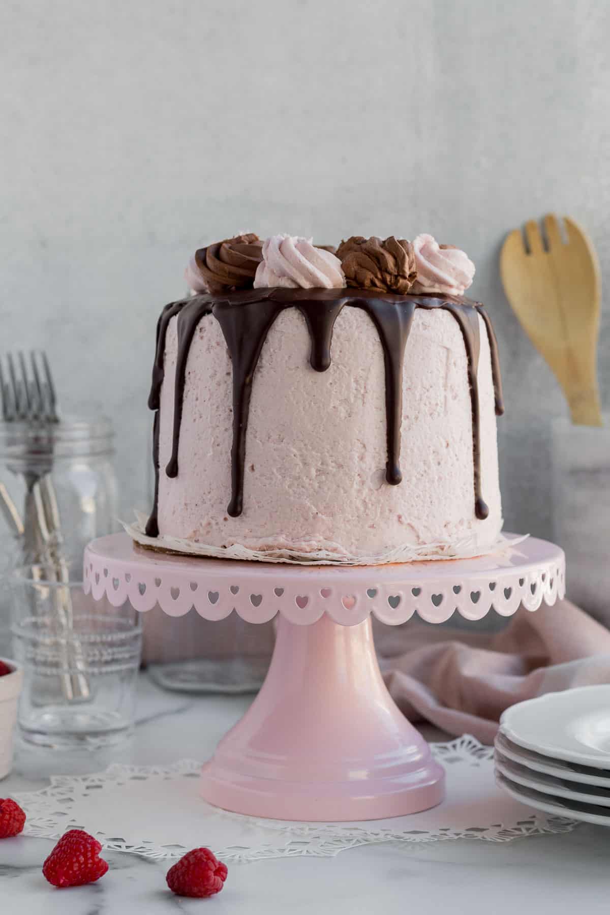 chocolate raspberry mousse cake with dripping chocolate ganache on a pink cake stand