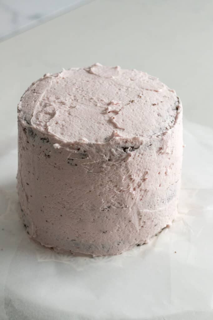 chocolate cake frosted with a crumb coat of raspberry frosting