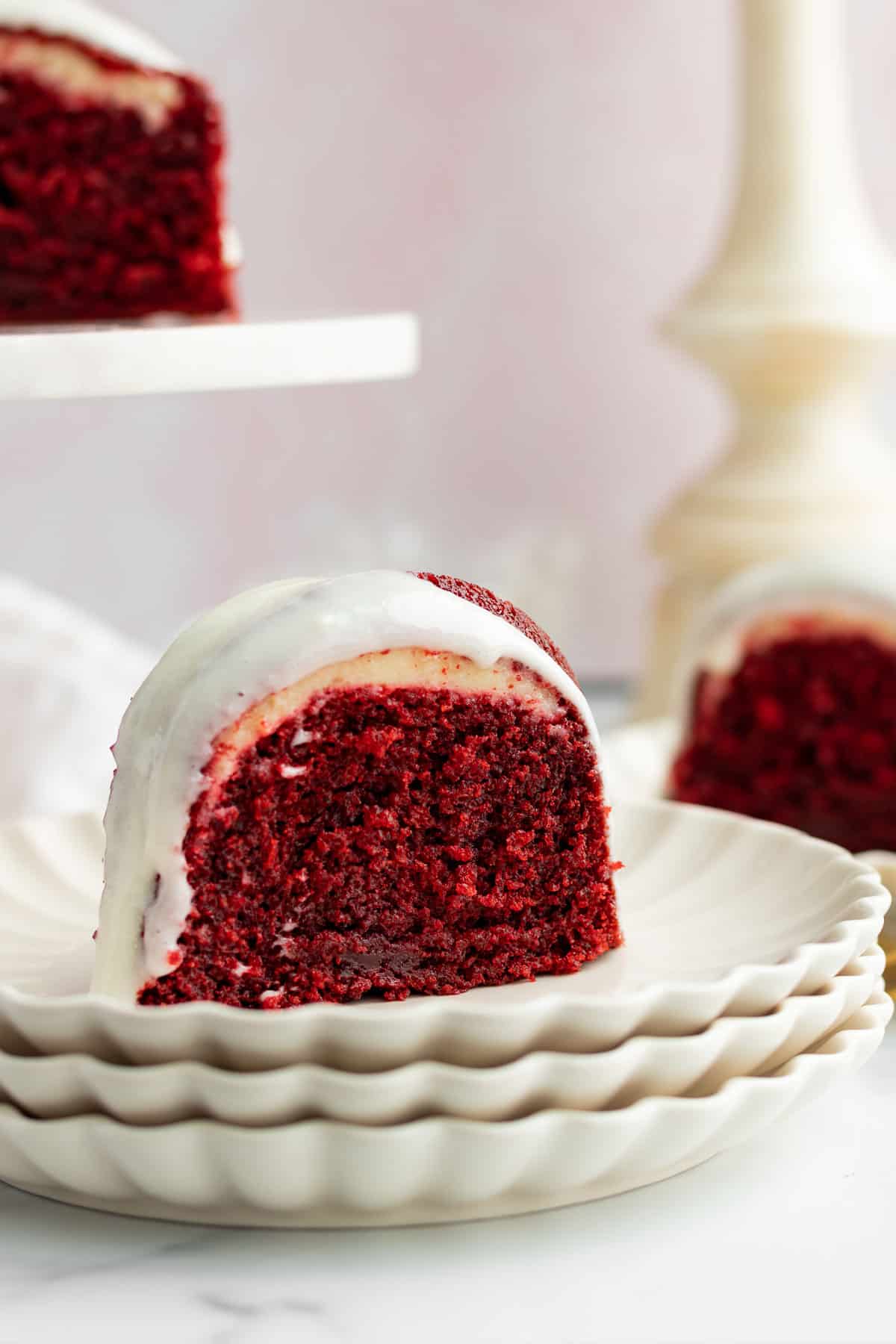 slice of red velvet bundt cake on a stack of cream colored plates