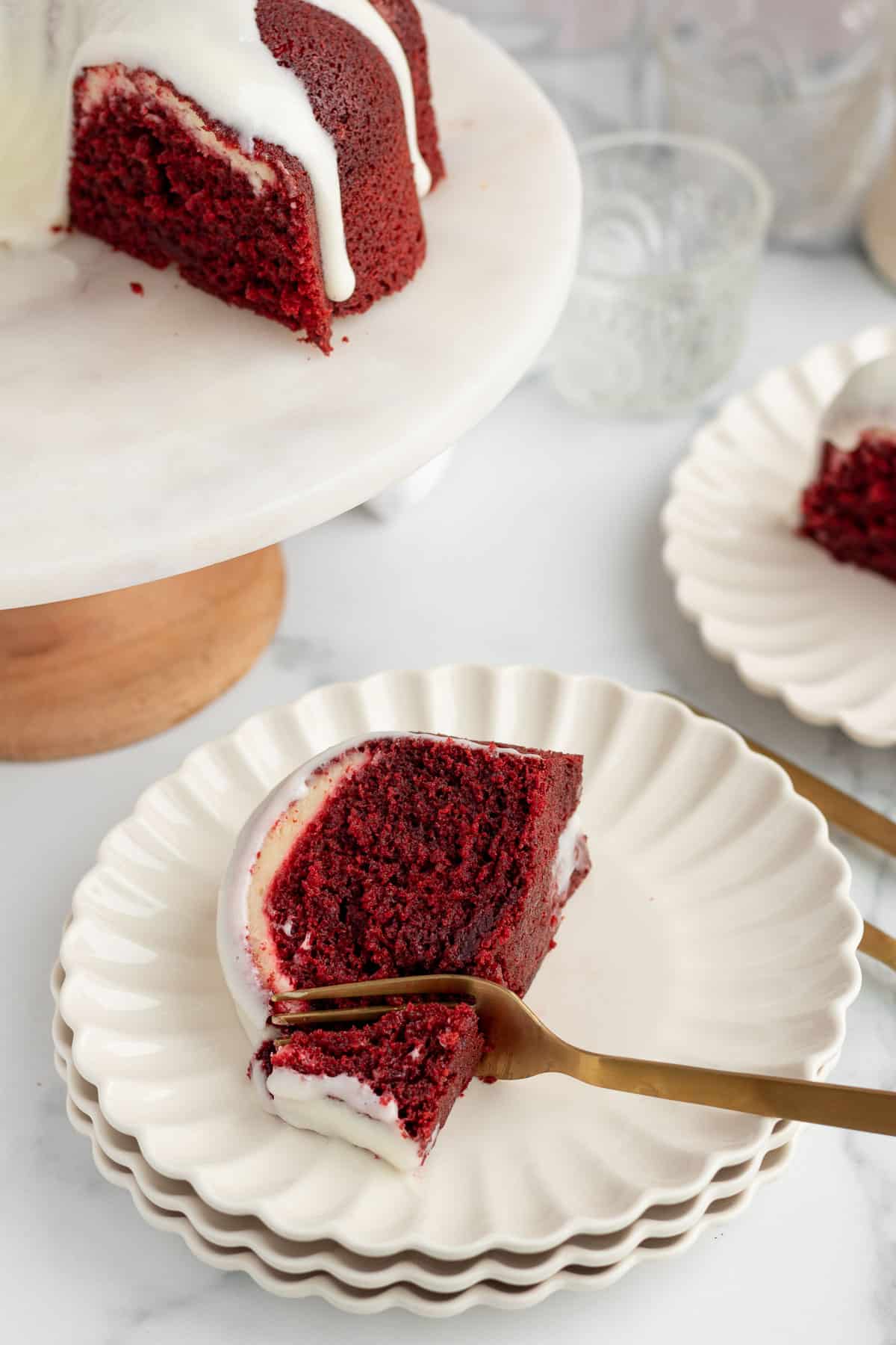 red velvet bundt cake slice on a stack of scalloped white plates