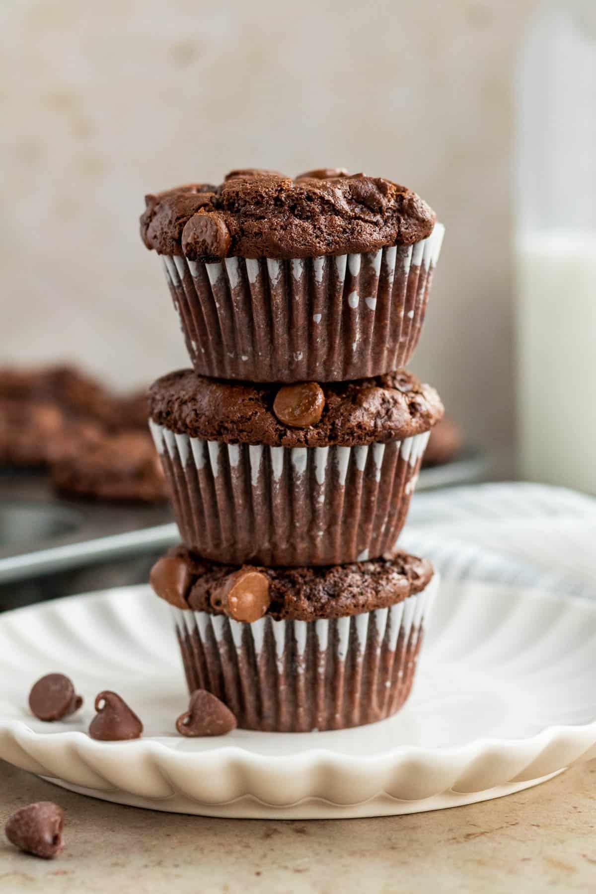 stack of 3 triple chocolate muffins on a white scalloped plate