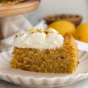 a slice of lemon pistachio cake on a cream scalloped plate