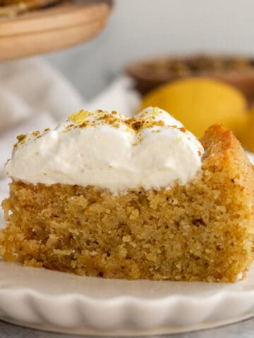 a slice of lemon pistachio cake on a cream scalloped plate