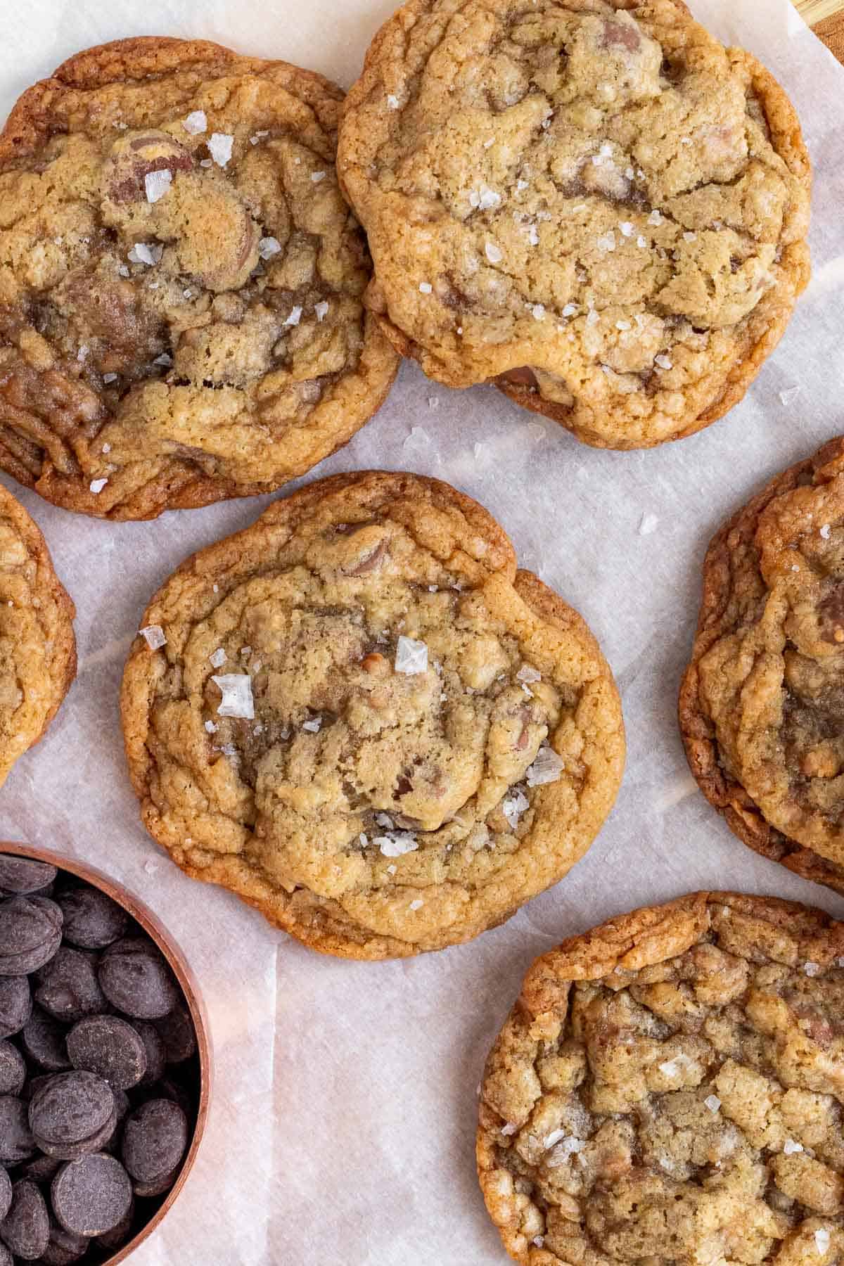 salted toffee chocolate chip cookies in a pile with a measuring cup of chocolate chip