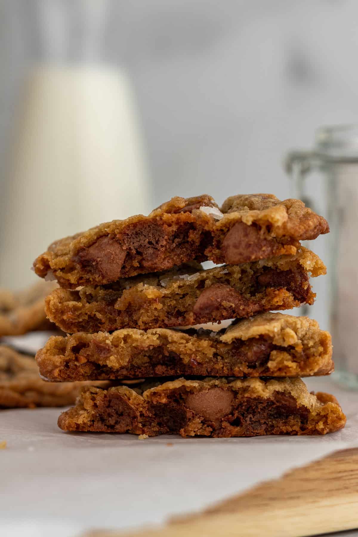 stack of cut open salted toffee chocolate chip cookies with a bottle of milk in the background