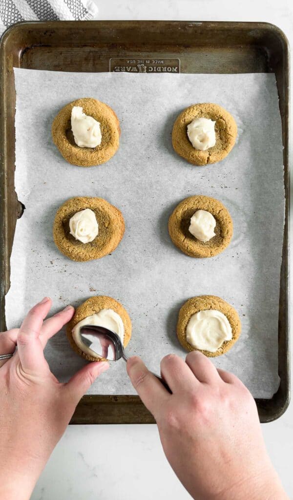 spreading cheesecake filling onto strawberry cheesecake cookies