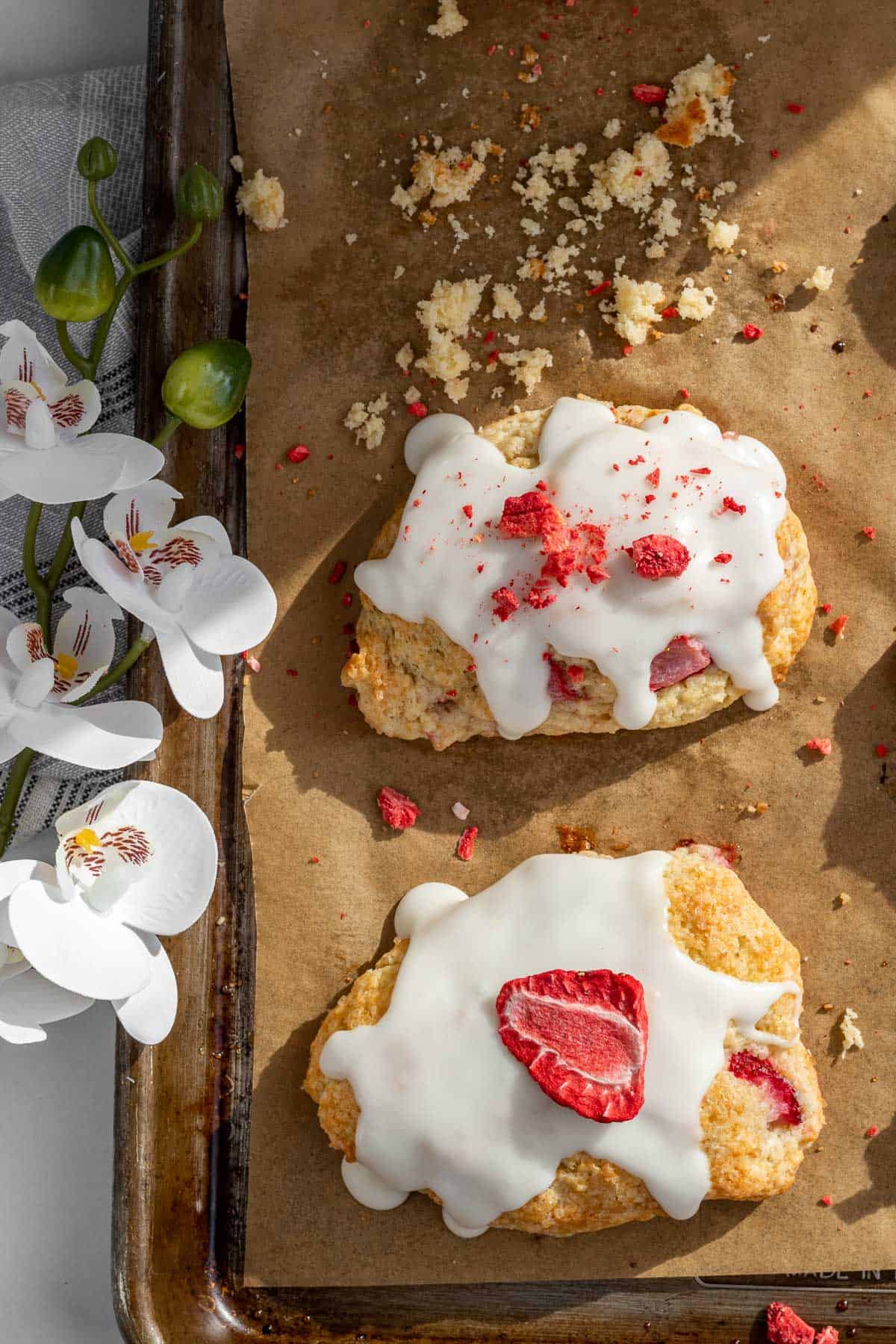 strawberry scones on a baking sheet with orchids next to it