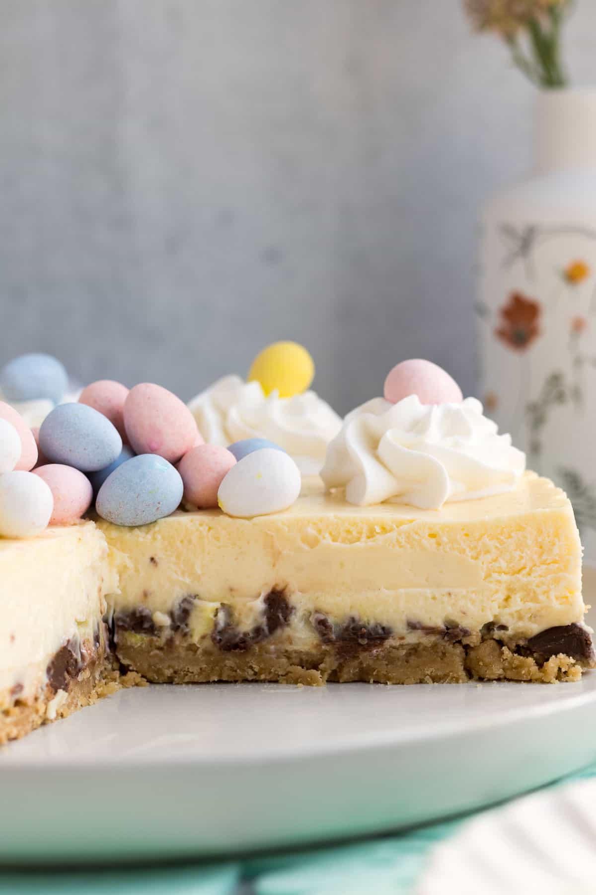 close up of an Easter egg cheesecake on a gray plate with a piece cut out showing the inside of the cheesecake