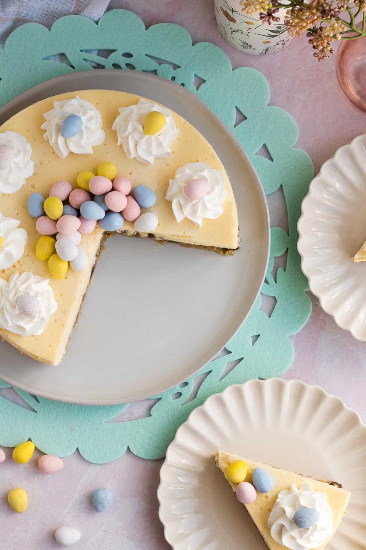 top view of an Easter egg cheesecake with 2 slices cut out and on scalloped plates to the side