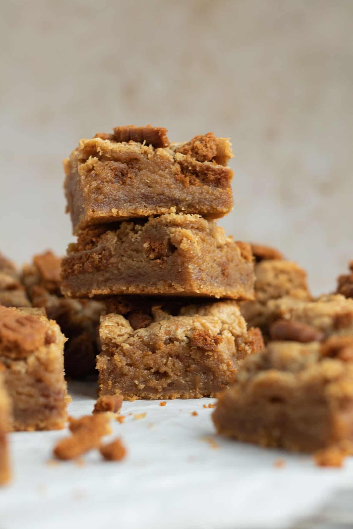 a stack of 3 biscoff blondies with other blondies scattered around them