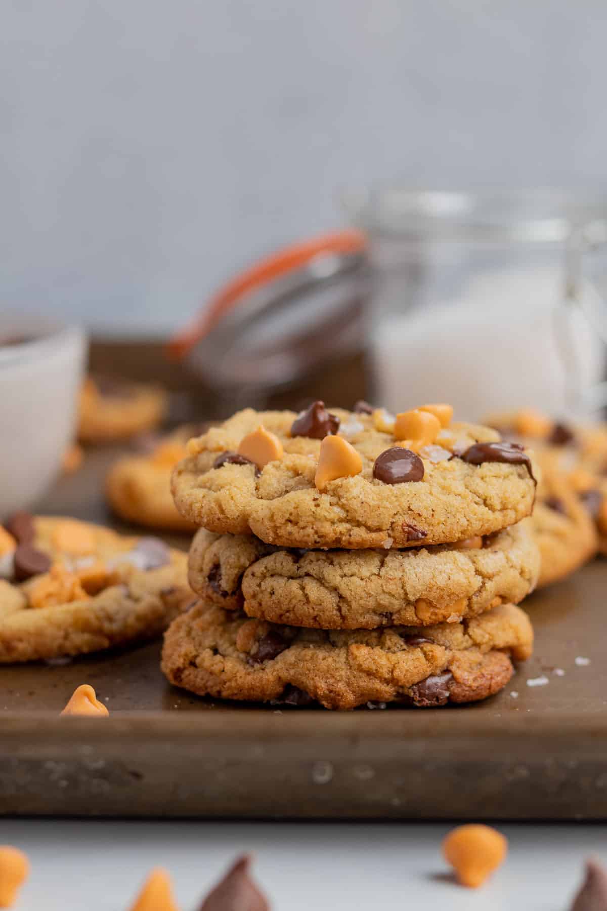 a stack of 3 chocolate chip butterscotch cookies with a glass jar of salt in the background