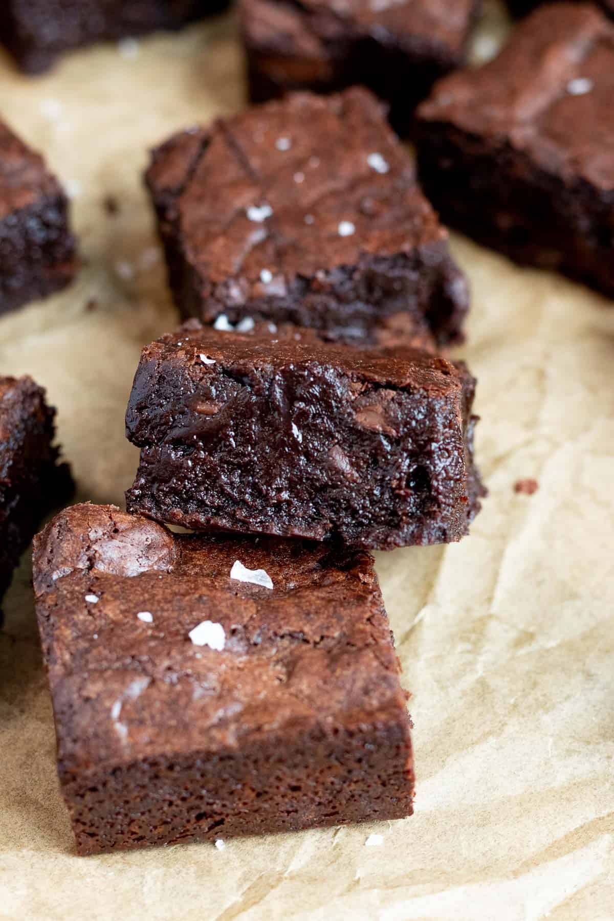 dark chocolate brownie leaning on another brownie with sea salt on top