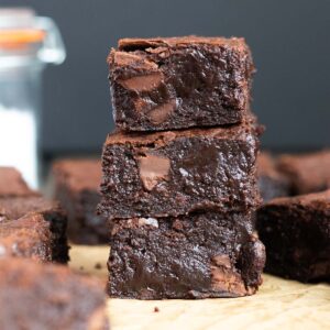 a stack of three dark chocolate brownies against a dark background