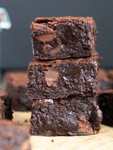 a stack of three dark chocolate brownies against a dark background