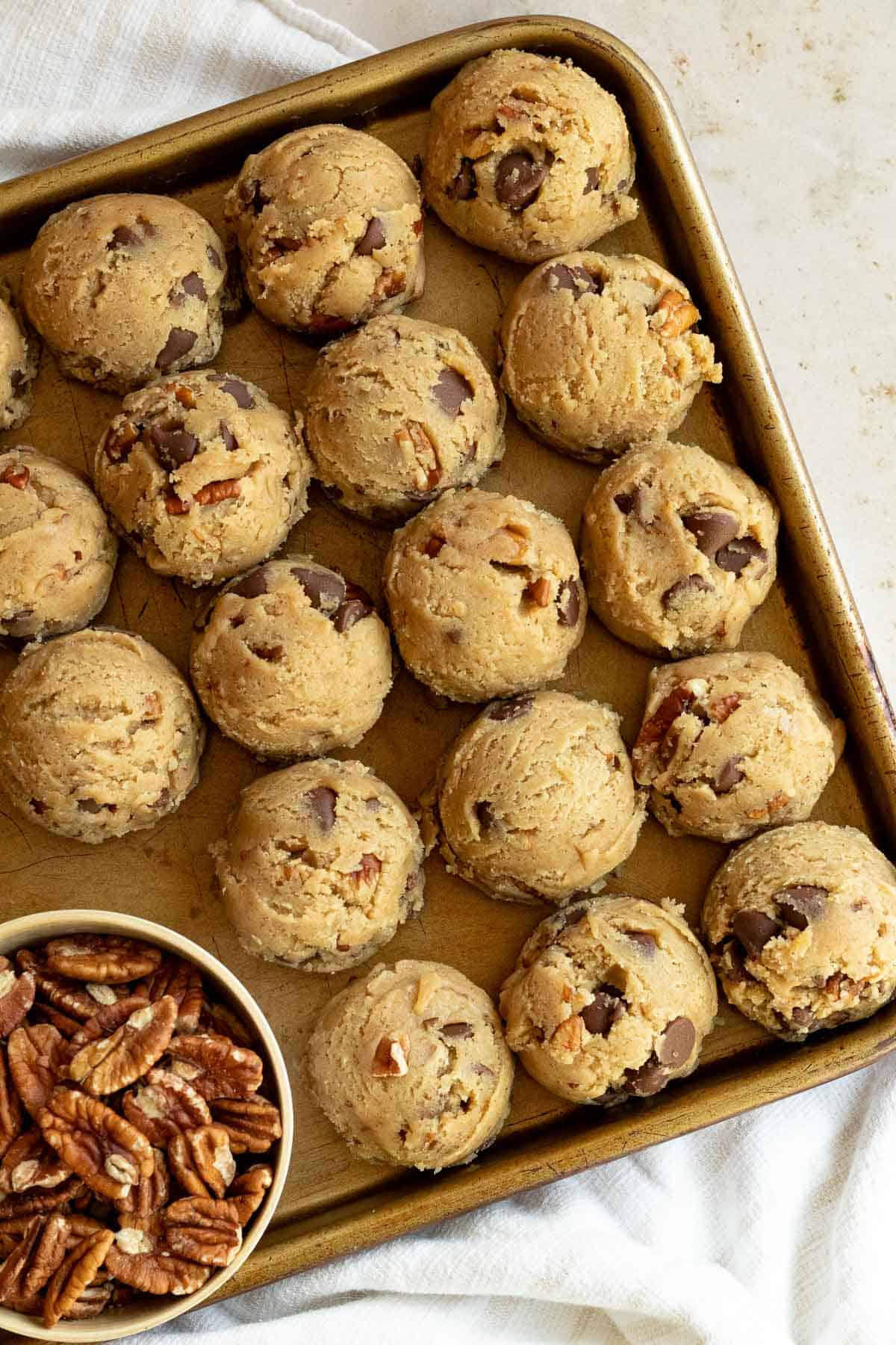 balls of pecan chocolate chip cookie dough on a cookie sheet