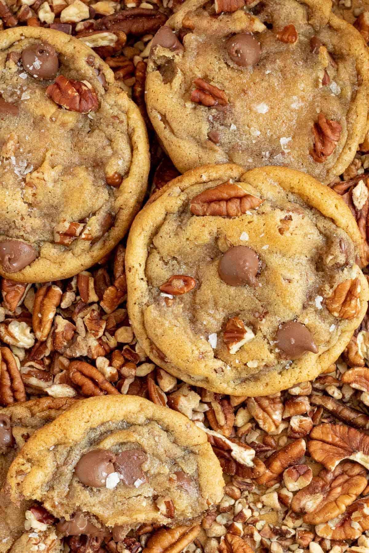 pecan chocolate chip cookies laying on top of chopped pecans