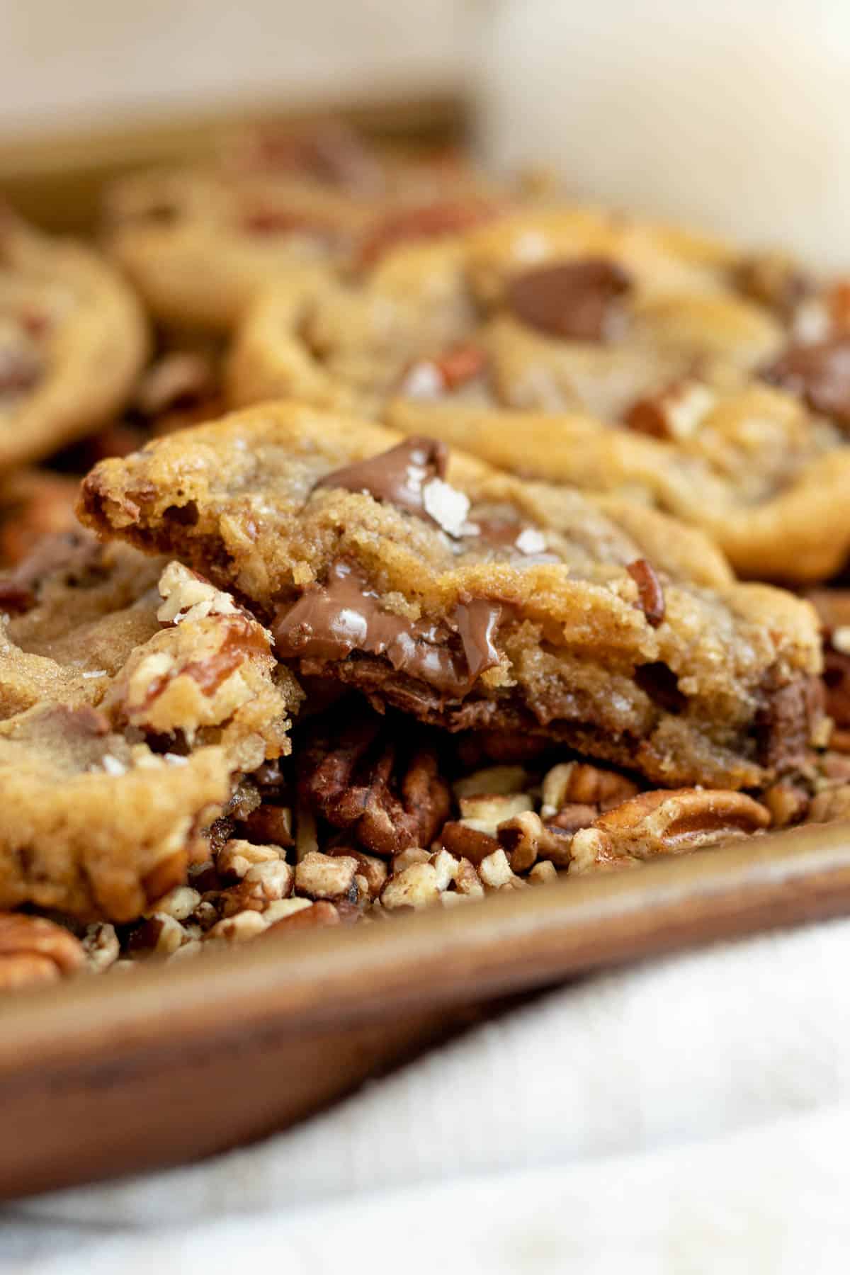 pecan chocolate chip cookie split in half showing melted chocolate chips