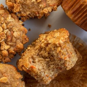 banana carrot muffin topped with granola, laying on its side with a bite out of it