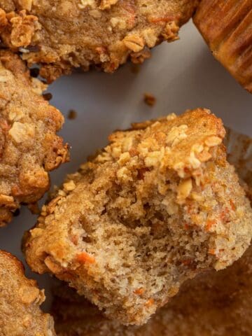banana carrot muffin topped with granola, laying on its side with a bite out of it