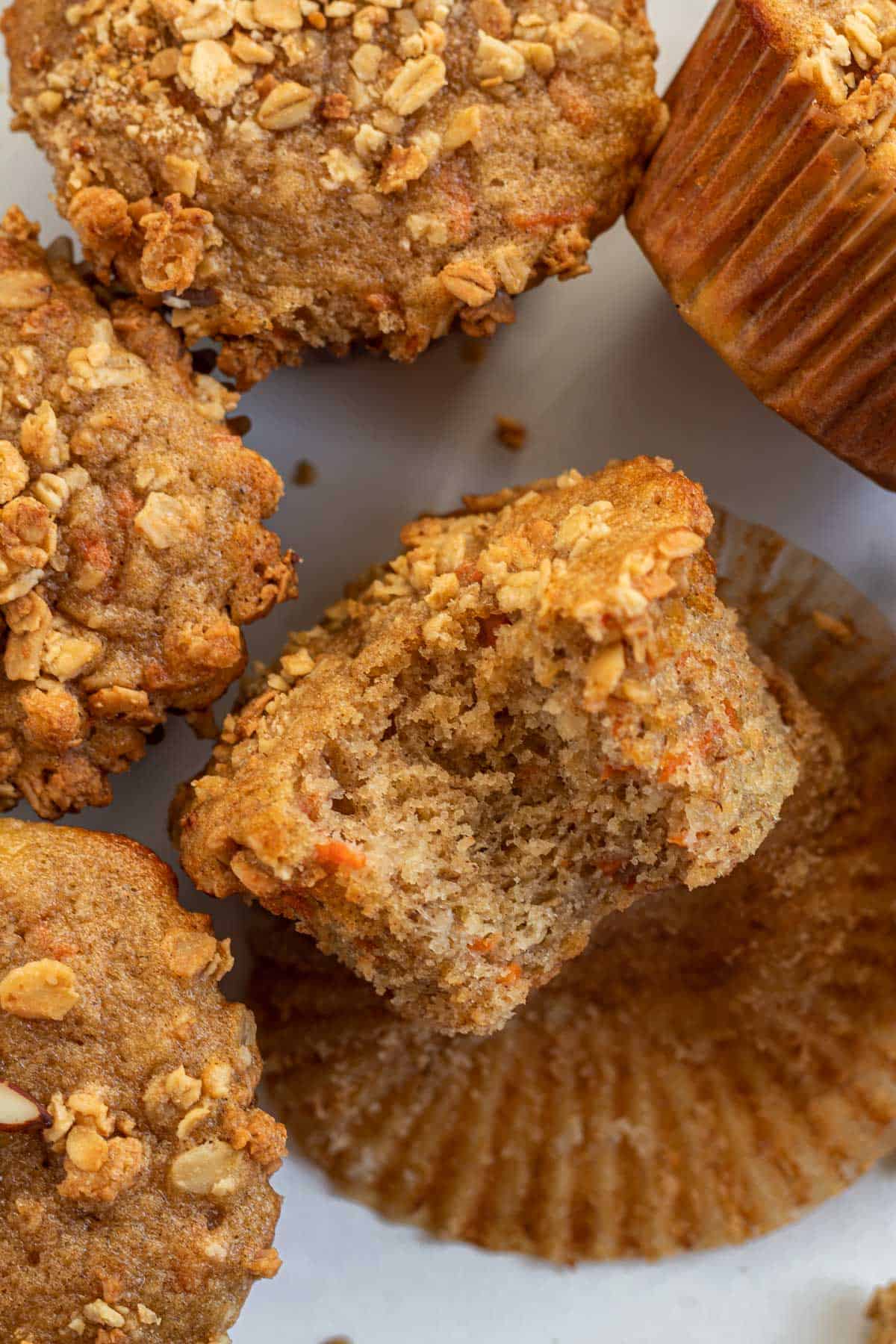 banana carrot muffin topped with granola, laying on its side with a bite out of it