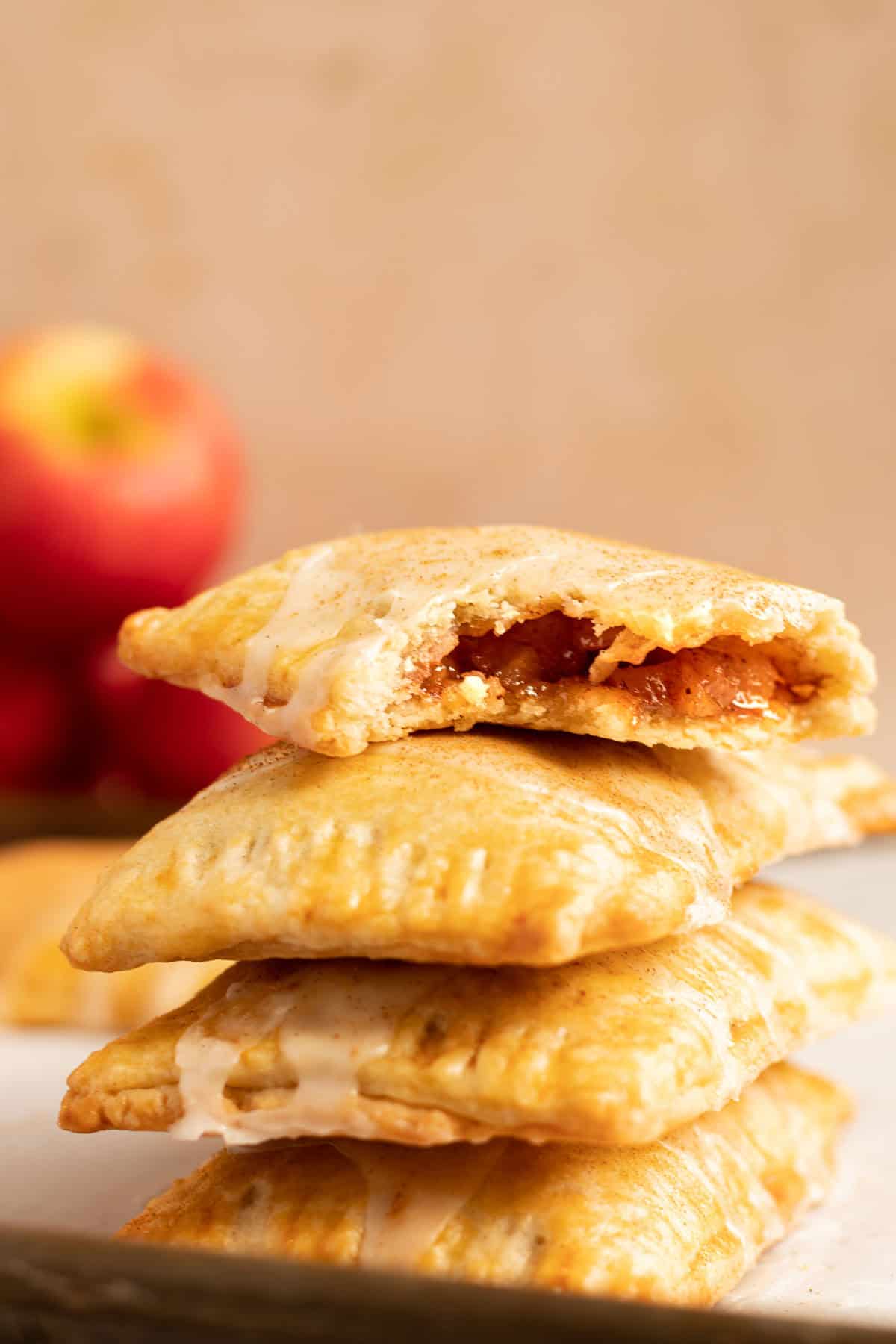 a stack of cinnamon apple pop tars with red apples in the background