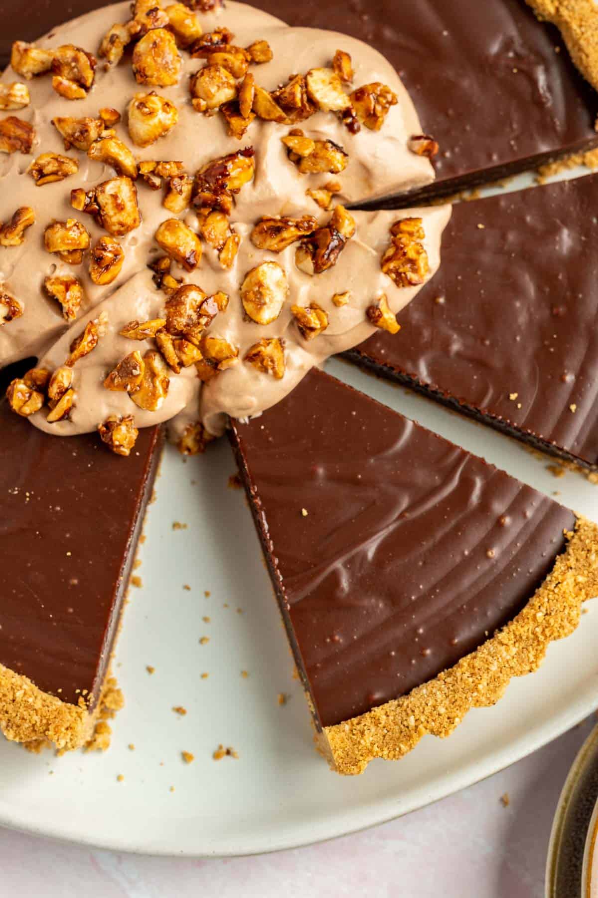 nutella tart sliced into wedges with a pile of nutella whipped cream and candied hazelnuts on top